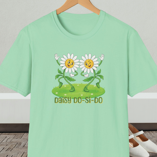Light green t-shirt with cartoon daisies and text 'Daisy Do-Si-Do' on a wooden hanger against a white wall.