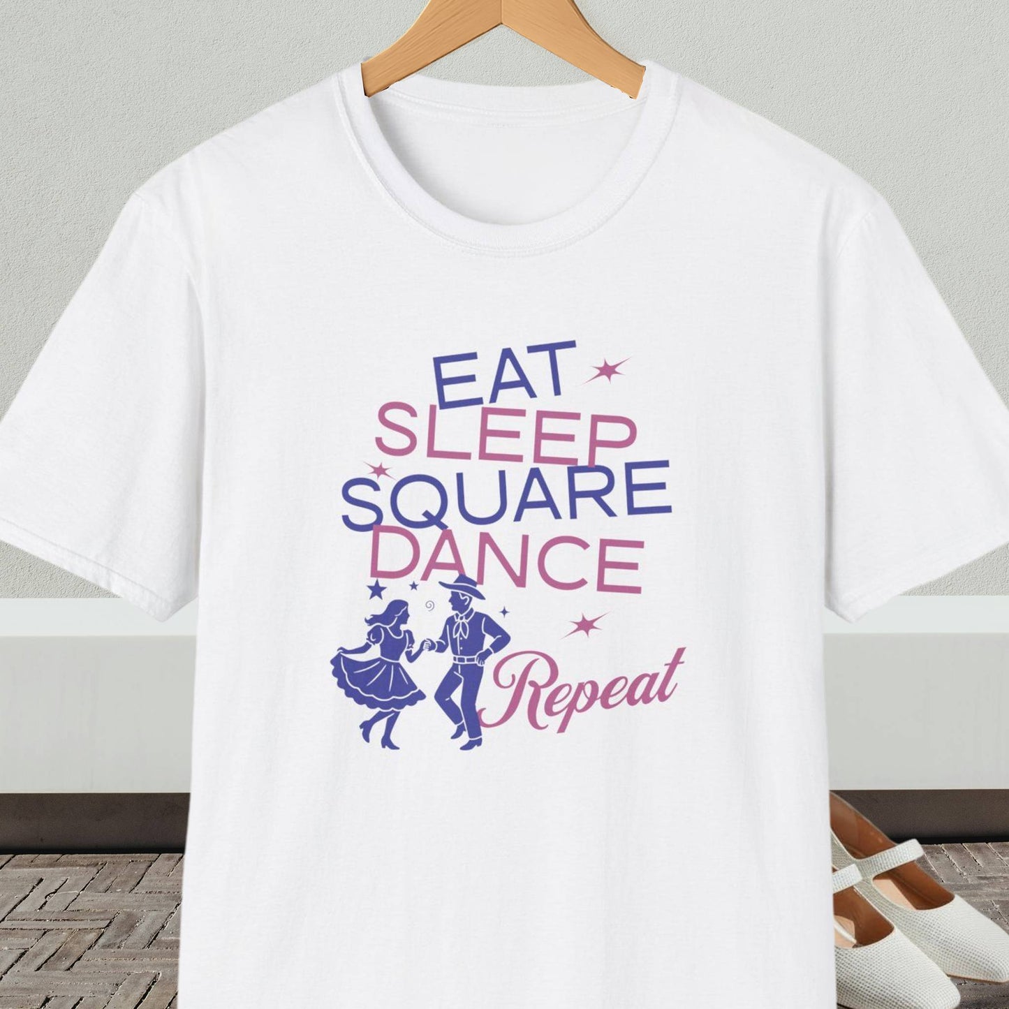 White t-shirt with 'Eat Sleep Square Dance Repeat' text and graphics on a hanger.