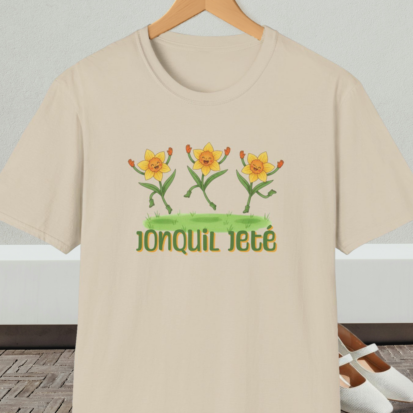 Beige t-shirt with cartoon dancing jonquils and 'Jonquil Jeté' text.