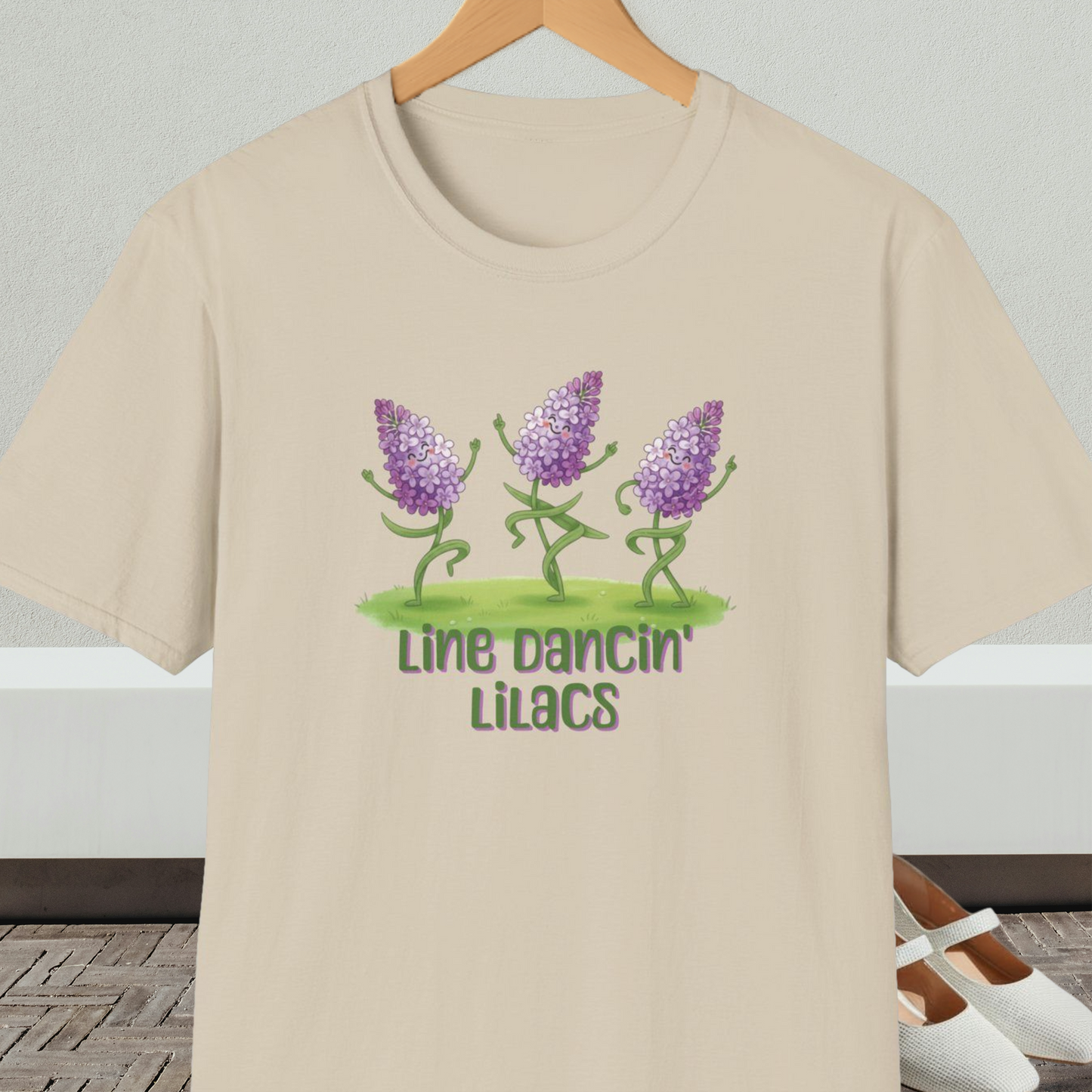 Beige t-shirt with text 'Line Dancin' Lilacs' and dancing flowers cartoon design.