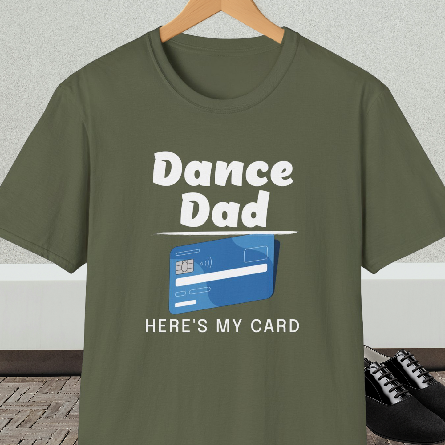 Military green t-shirt with 'Dance Dad, Here's My Card' text and credit card graphic, on a hanger with a neutral background.