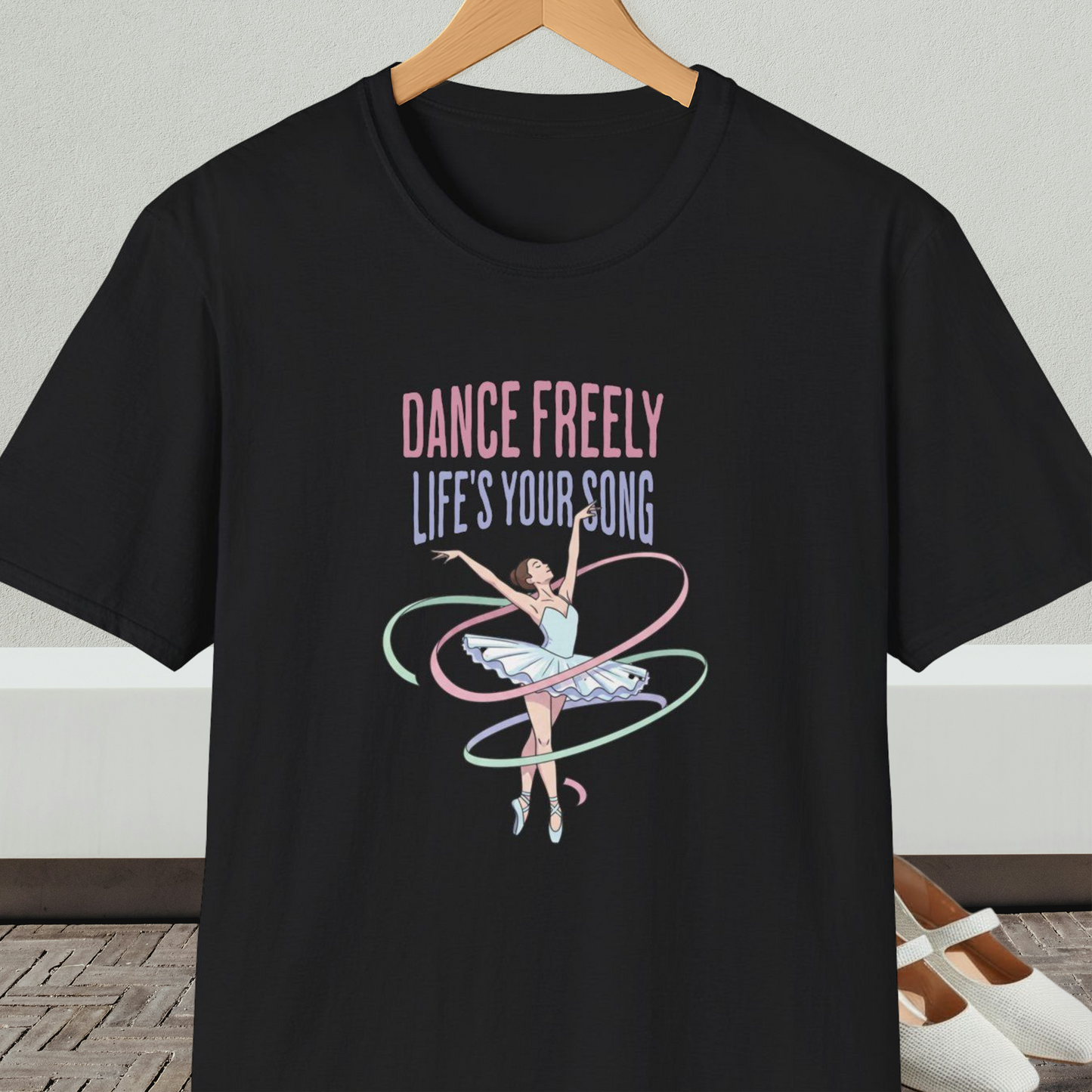 Black t-shirt with ballet design and text 'Dance Freely Life's Your Song', on a hanger against a neutral background