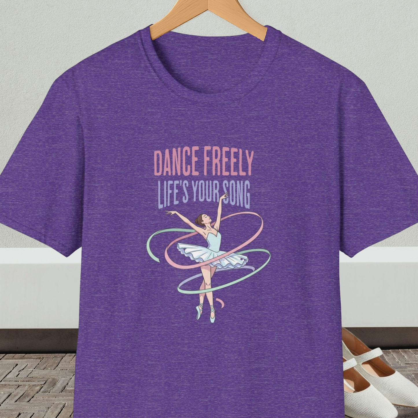 Purple heather t-shirt with ballet design and text 'Dance Freely Life's Your Song', on a hanger against a neutral background