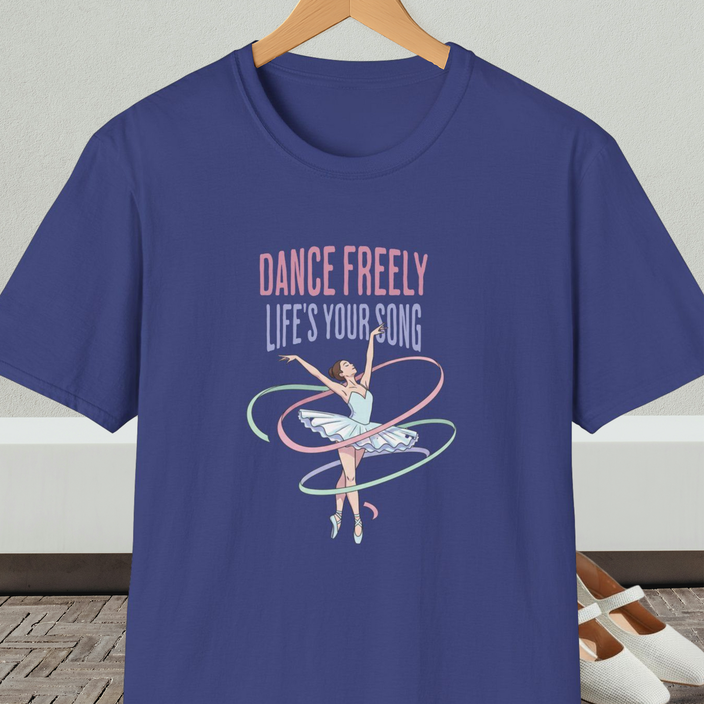 Blue t-shirt with ballet design and text 'Dance Freely Life's Your Song', on a hanger against a neutral background
