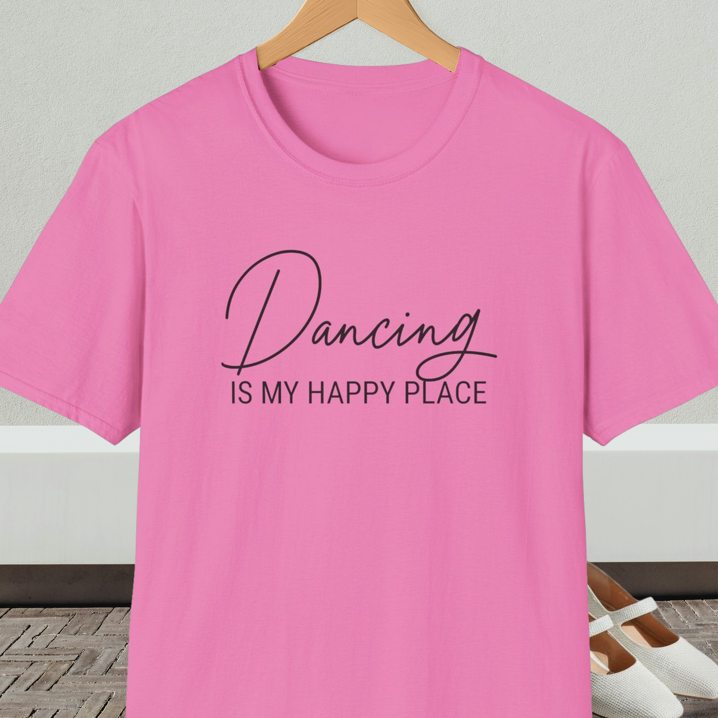 Pink t-shirt with 'Dancing IS MY HAPPY PLACE' text on a hanger against a neutral background.