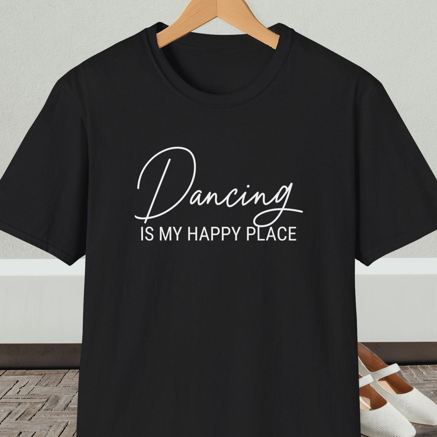 Black t-shirt with 'Dancing IS MY HAPPY PLACE' text on a hanger against a neutral background.