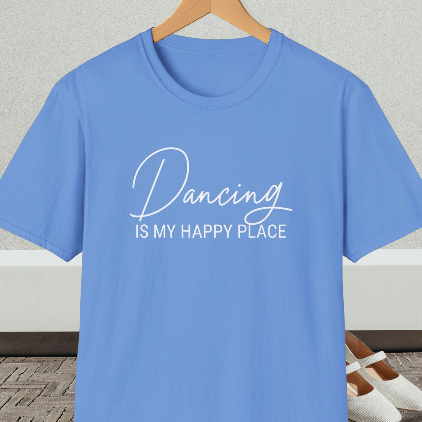Medium blue t-shirt with 'Dancing IS MY HAPPY PLACE' text on a hanger against a neutral background.