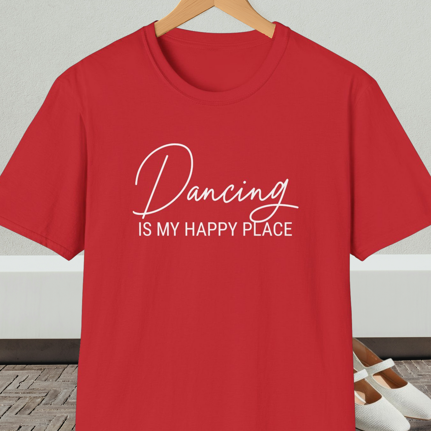 Red t-shirt with 'Dancing IS MY HAPPY PLACE' text on a hanger against a neutral background.