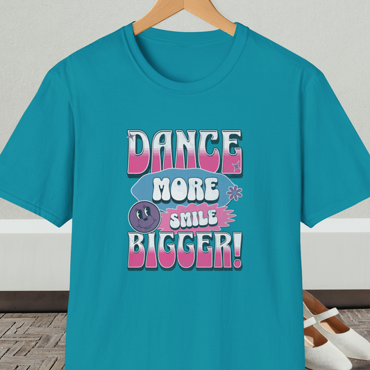 Turquoise t-shirt with 'Dance More Smile Bigger!' retro text, on a hanger against a neutral background.