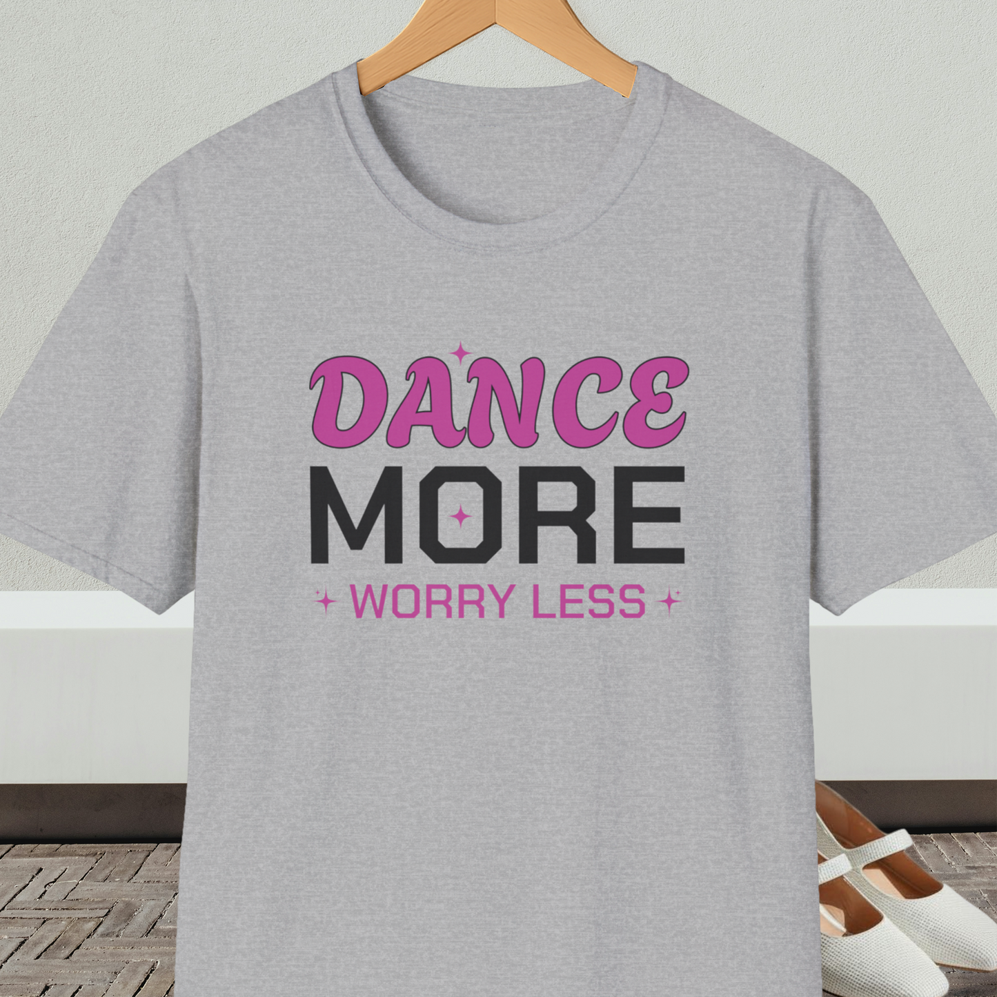 Gray t-shirt with 'Dance More Worry Less' text, on a hanger against a neutral background