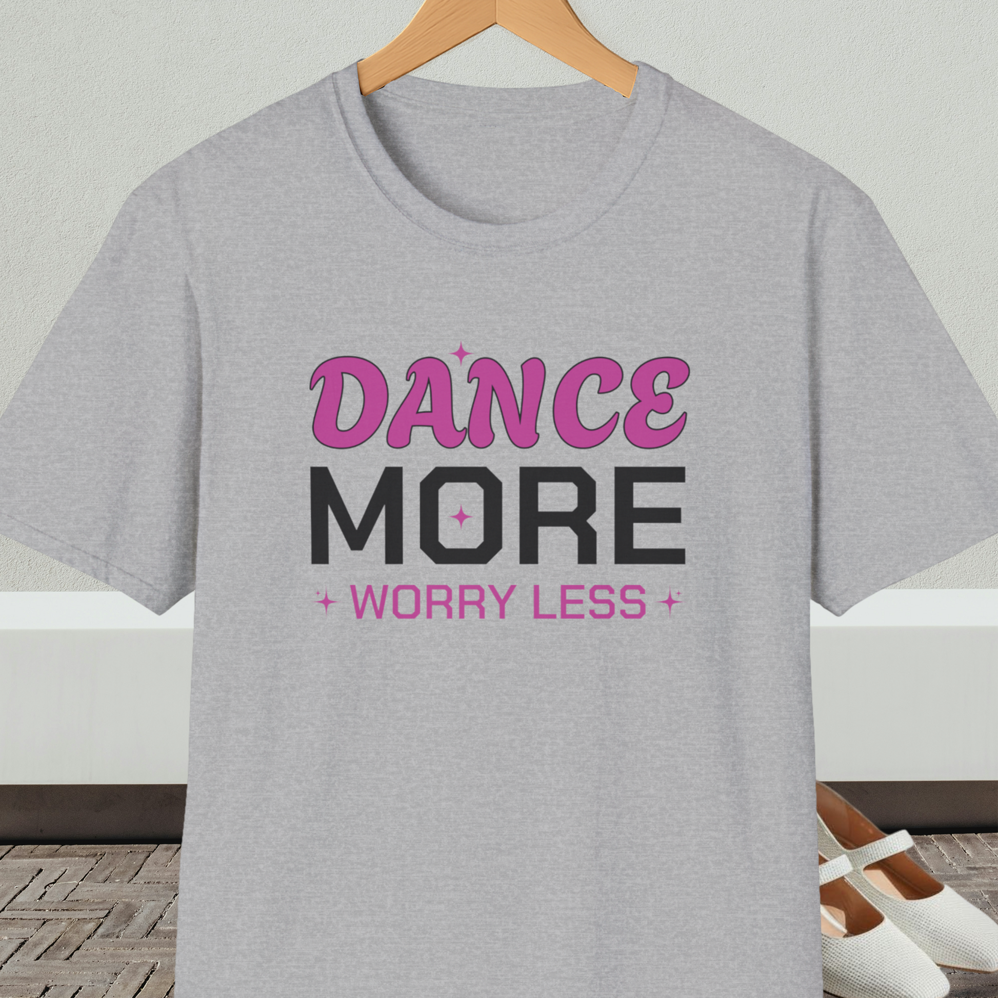 Gray t-shirt with 'Dance More Worry Less' text, on a hanger against a neutral background
