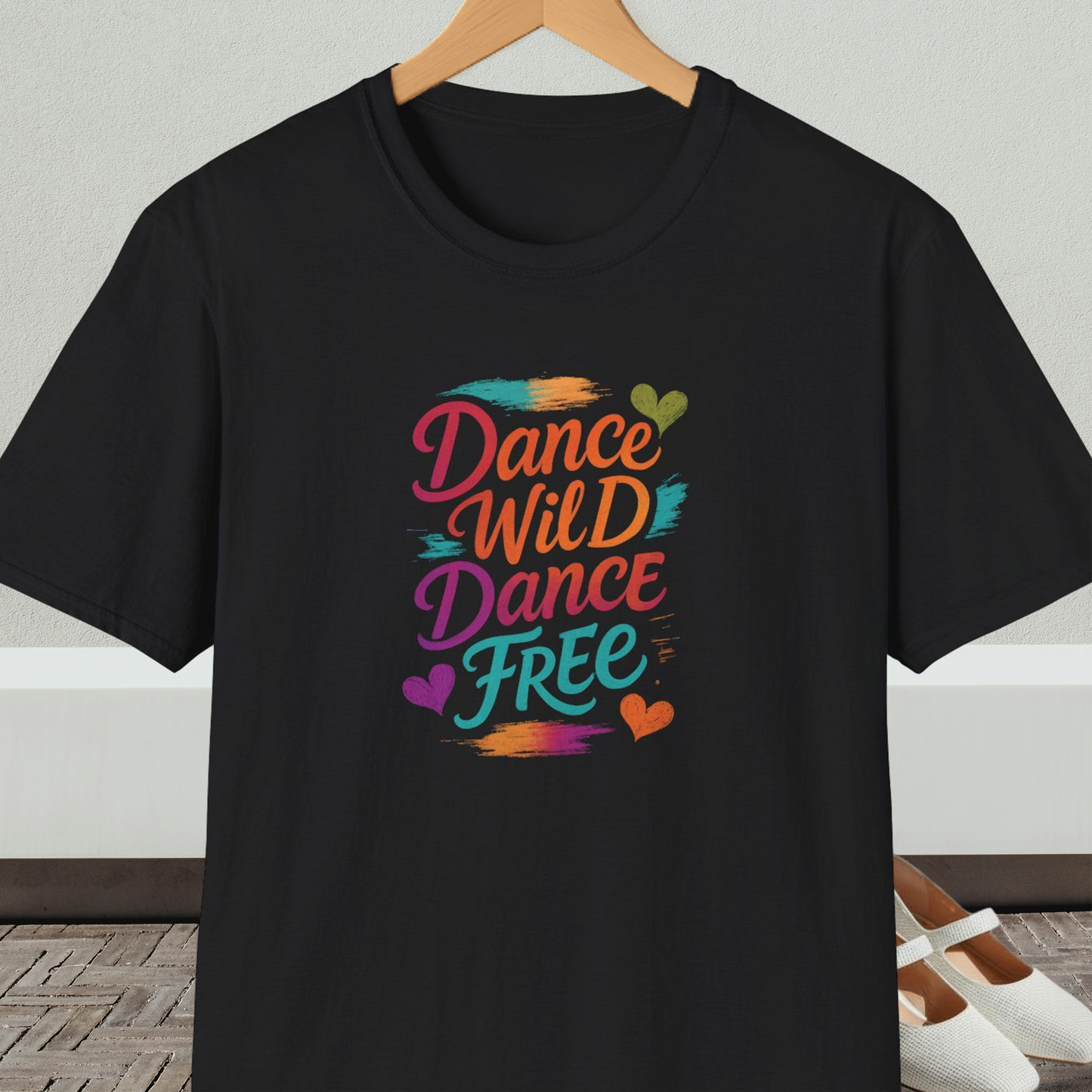 Black t-shirt with colorful 'Dance Wild Dance Free' text, on a hanger against a neutral background.