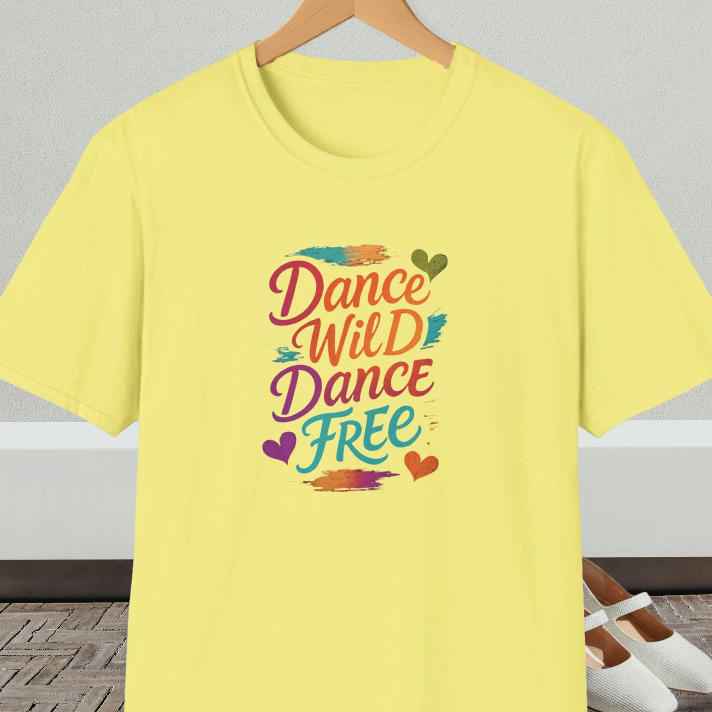 Yellow t-shirt with colorful 'Dance Wild Dance Free' text, on a hanger against a neutral background.