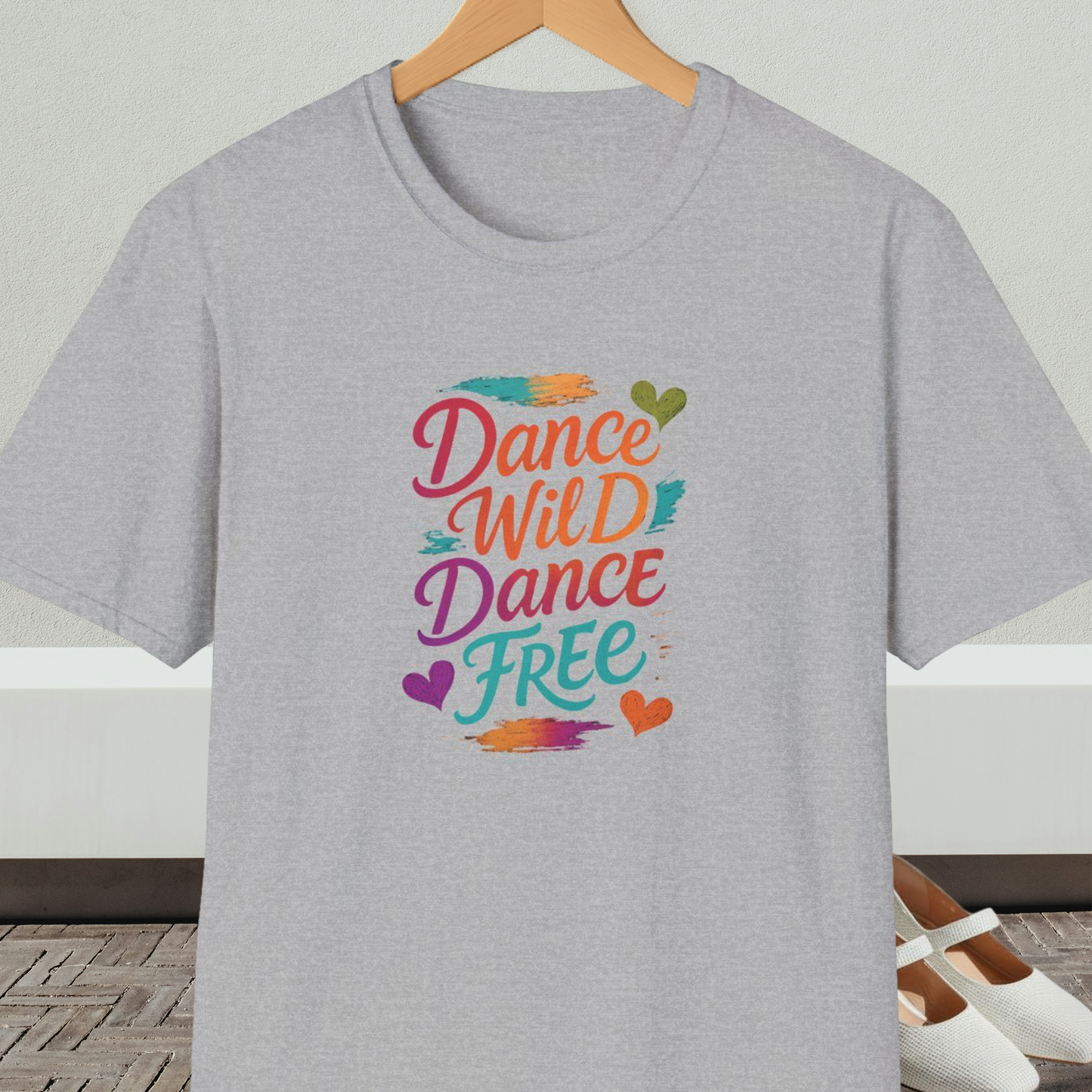 Gray t-shirt with colorful 'Dance Wild Dance Free' text, on a hanger against a neutral background.