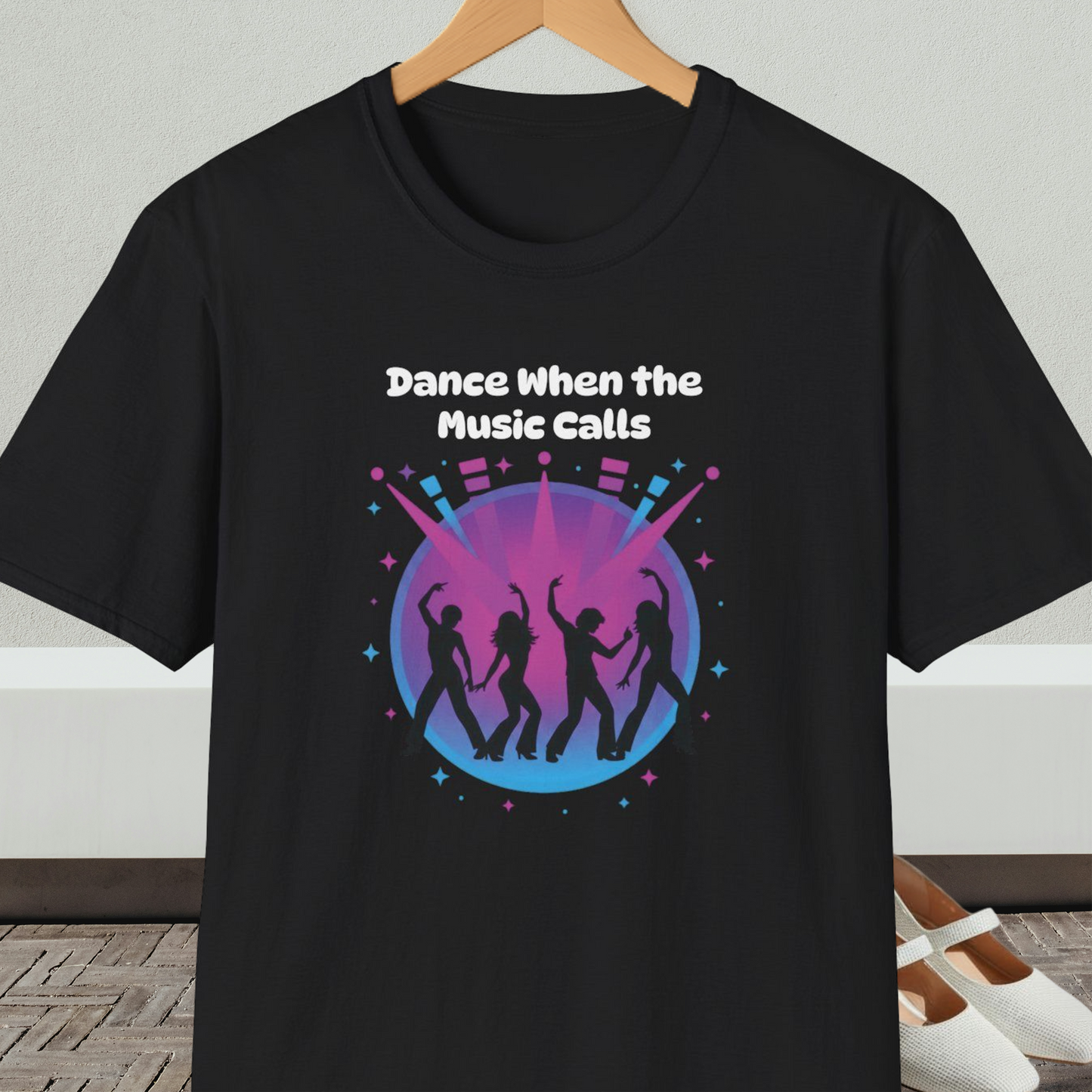 Black t-shirt with 'Dance When the Music Calls' dance club design, on a hanger against a neutral background.