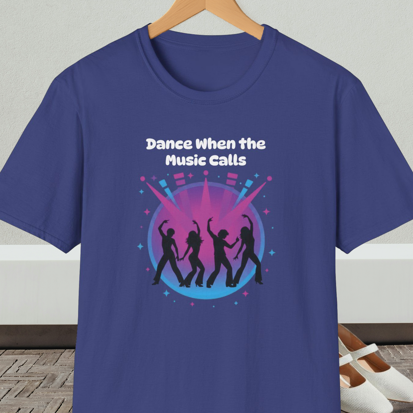 Blue t-shirt with 'Dance When the Music Calls' dance club design, on a hanger against a neutral background.