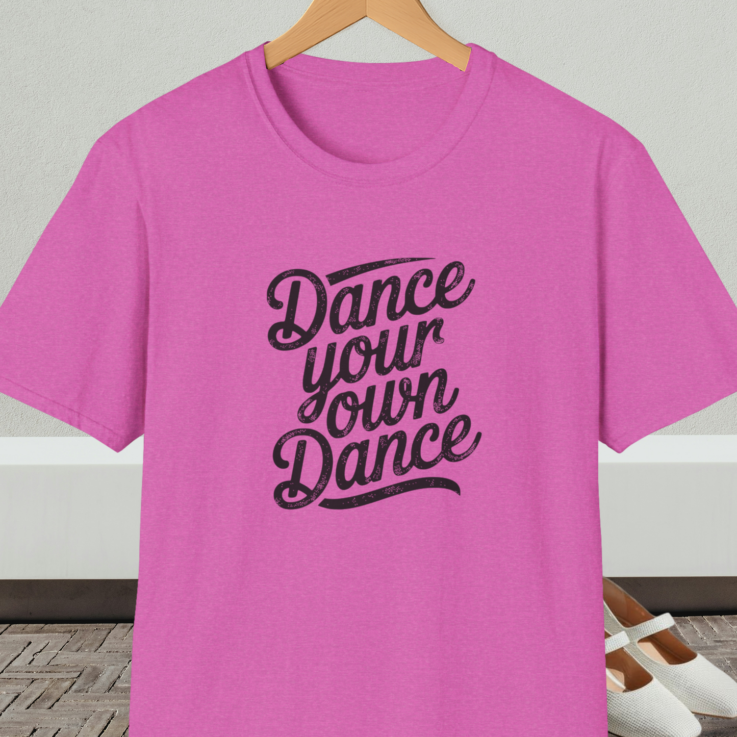 Orchid t-shirt with 'Dance your own Dance' text, on a hanger against a neutral background.