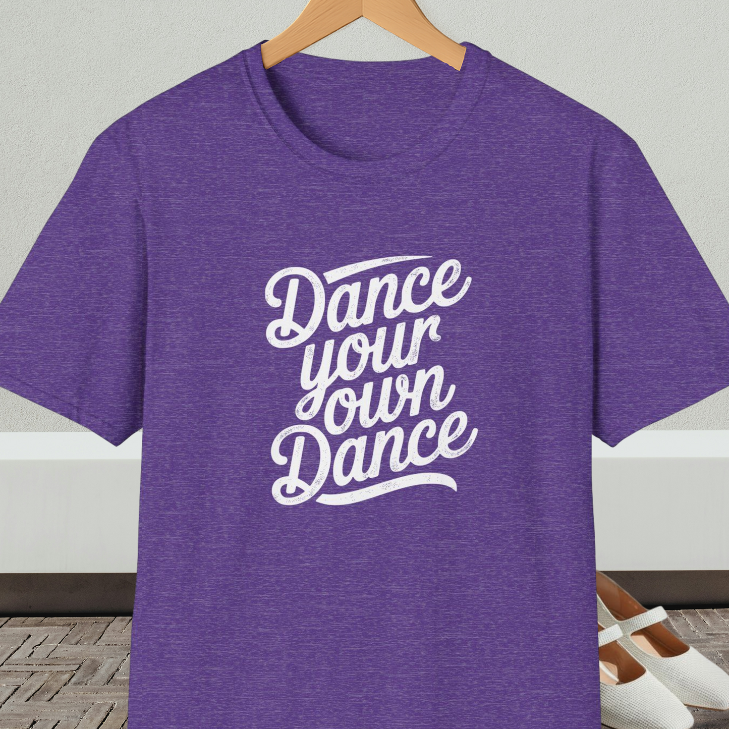 Heather purple t-shirt with 'Dance your own Dance' text, on a hanger against a neutral background