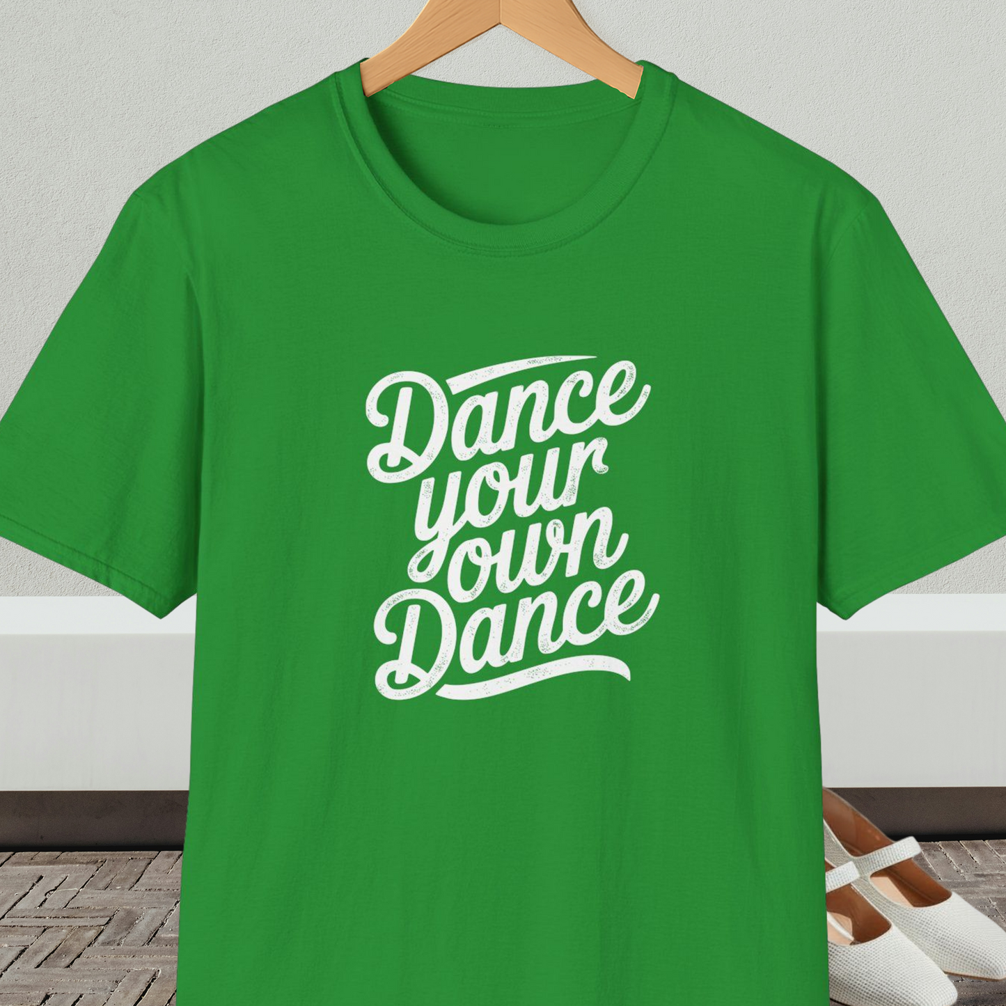 Irish green t-shirt with 'Dance your own Dance' text, on a hanger against a neutral background