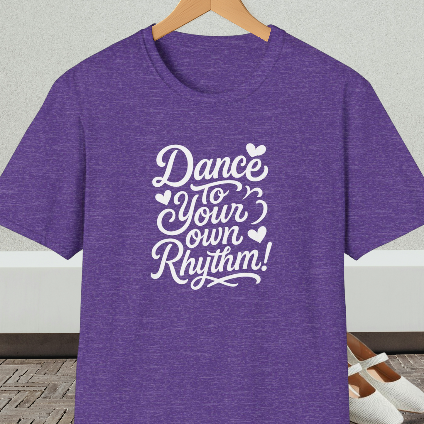 Purple t-shirt with 'Dance to Your Own Rhythm!' text, on a hanger against a neutral background.