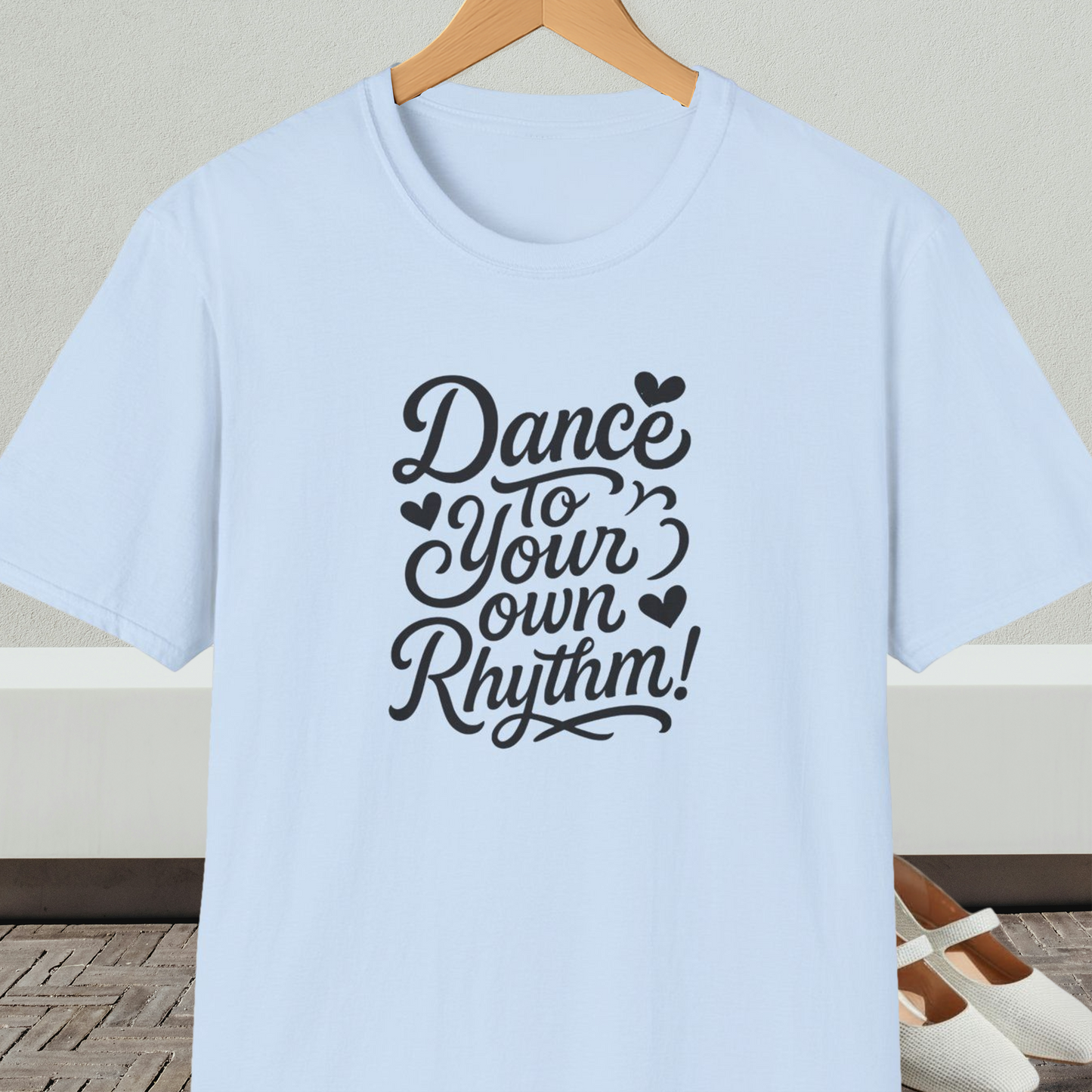 Light blue t-shirt with 'Dance to Your Own Rhythm!' text, on a hanger against a neutral background.