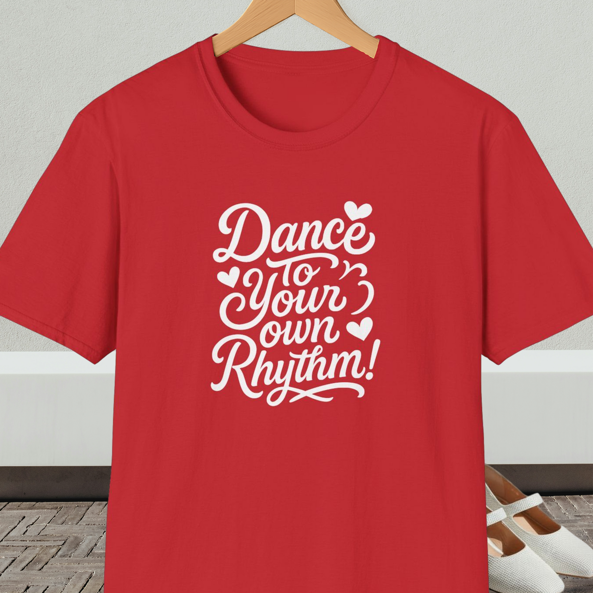 Red t-shirt with 'Dance to Your Own Rhythm!' text, on a hanger against a neutral background.