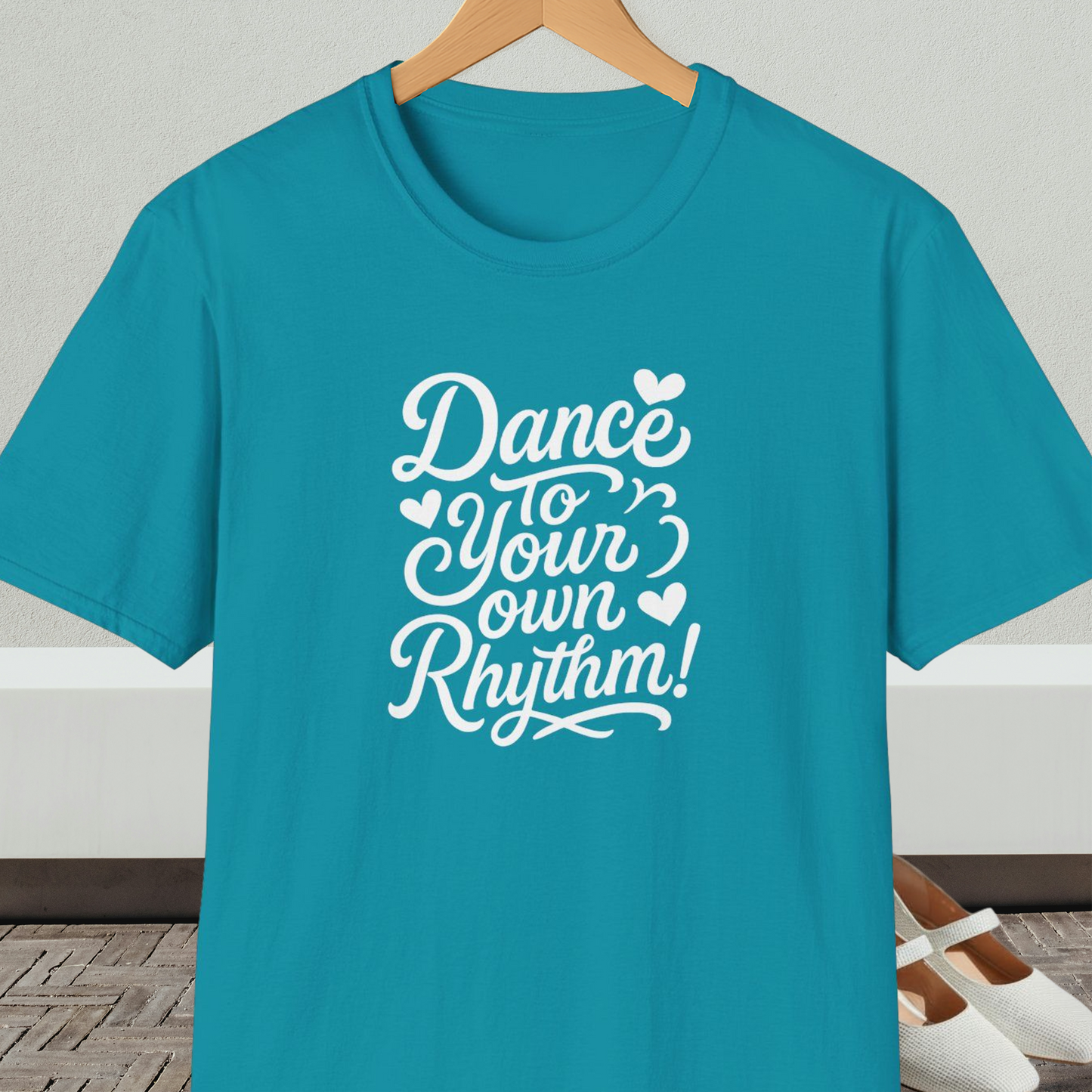 Teal t-shirt with 'Dance to Your Own Rhythm!' text, on a hanger against a neutral background.