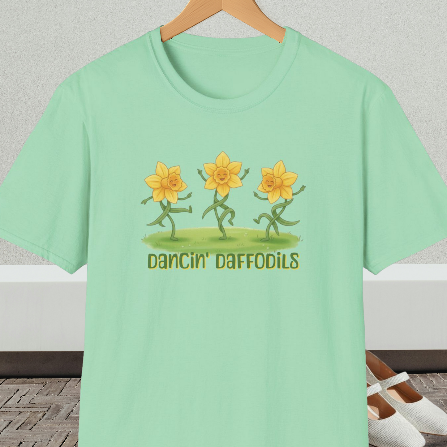 Mint green t-shirt with 'Dancin' Daffodils' design, on a hanger against a neutral background.