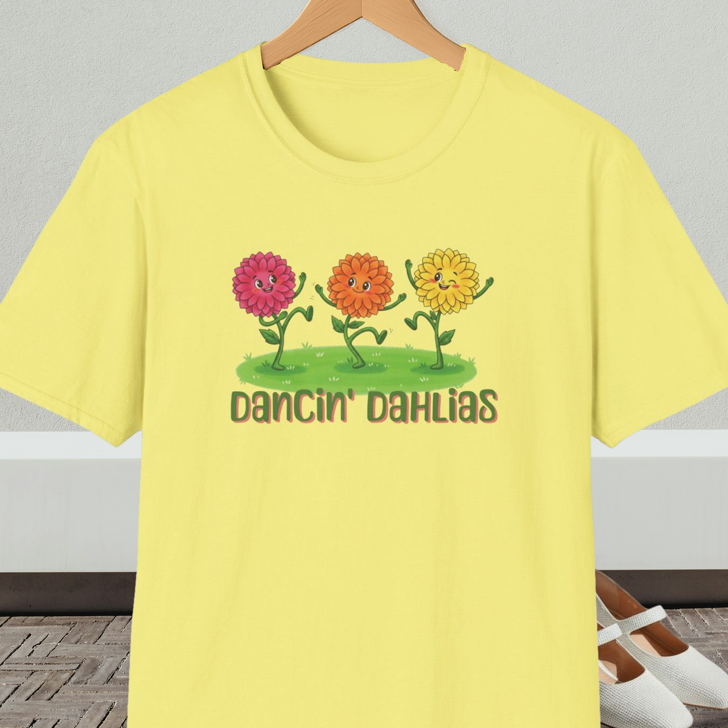 Yellow t-shirt with 'Dancin' Dahlias' design, on a hanger against a neutral background.