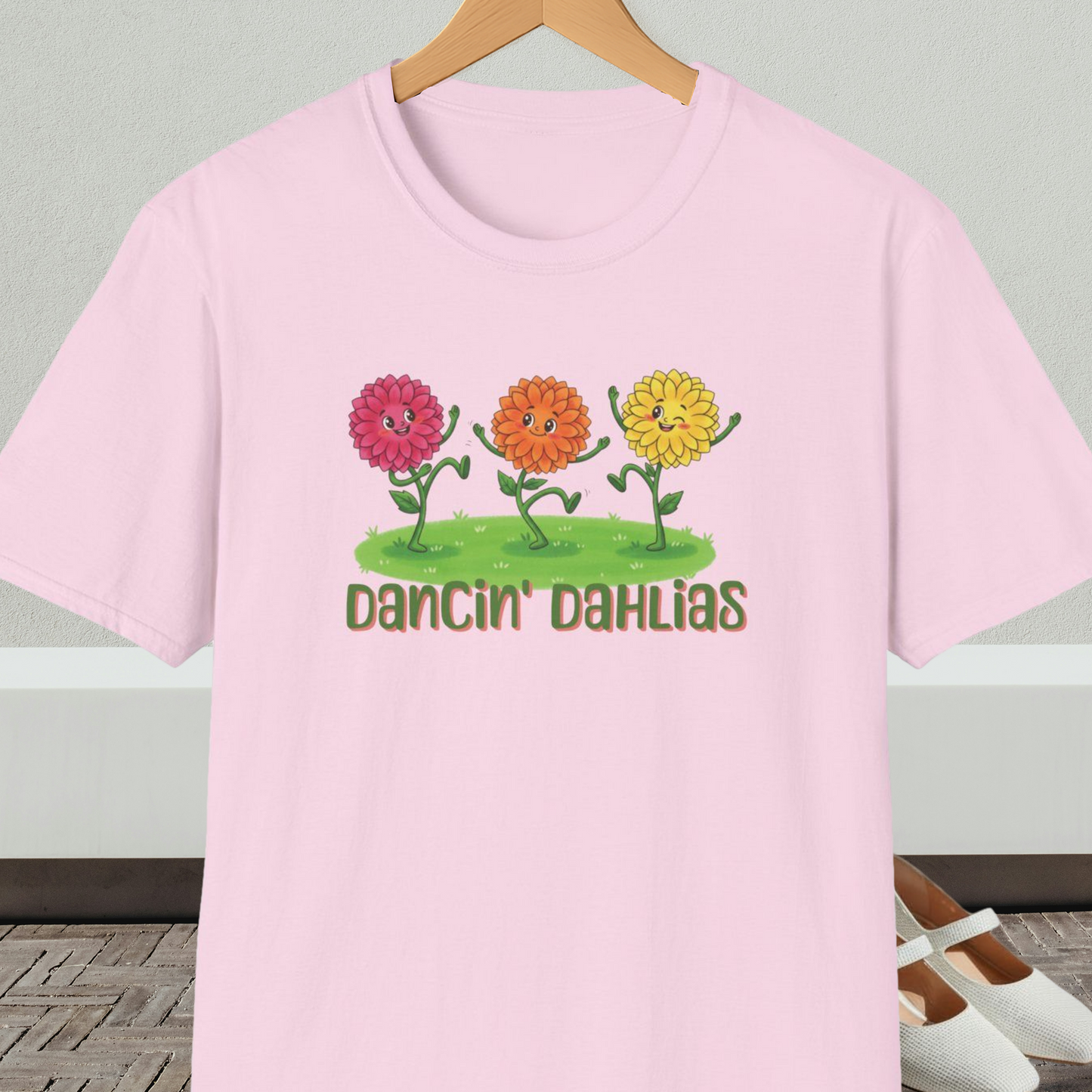 Light pink t-shirt with 'Dancin' Dahlias' design, on a hanger against a neutral background.