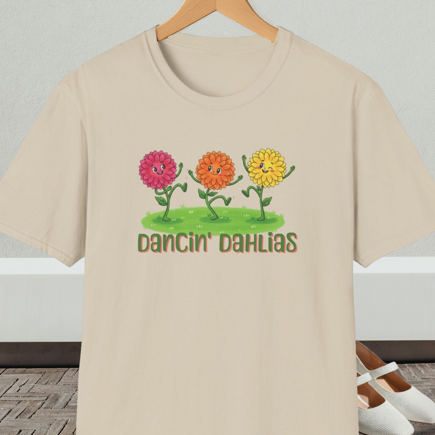 Beige t-shirt with 'Dancin' Dahlias' design, on a hanger against a neutral background.