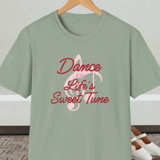 Sage green t-shirt with 'Dance to Life's Sweet Tune' text and pink musical note design, on a hanger against a neutral background.