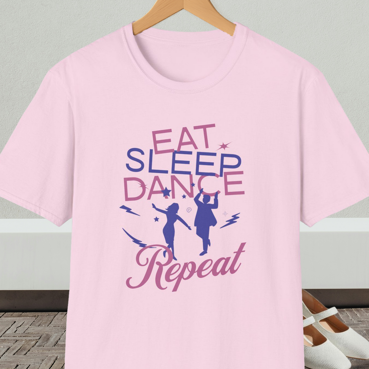 Light pink t-shirt with 'Eat Sleep Dance Repeat' text and graphics on a hanger.