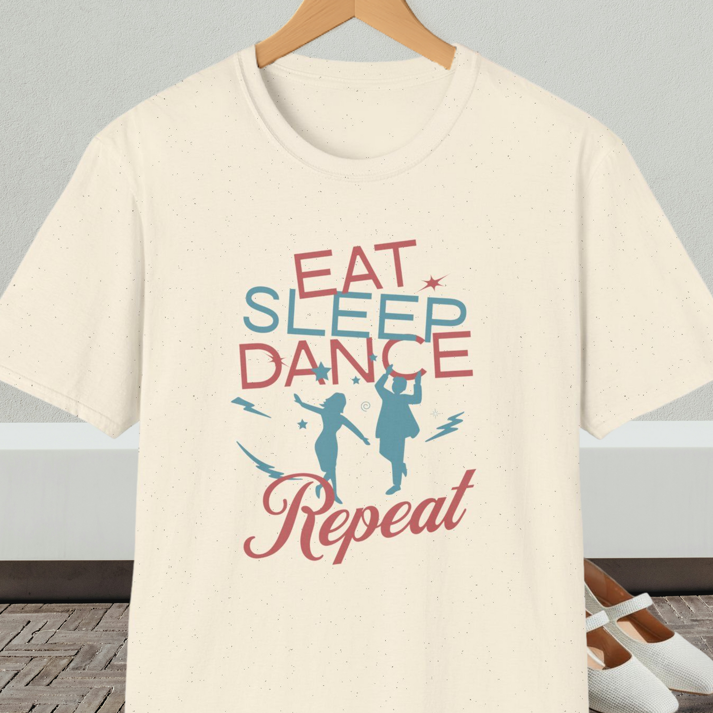 Natural beige t-shirt with 'Eat Sleep Dance Repeat' text and graphics on a hanger.
