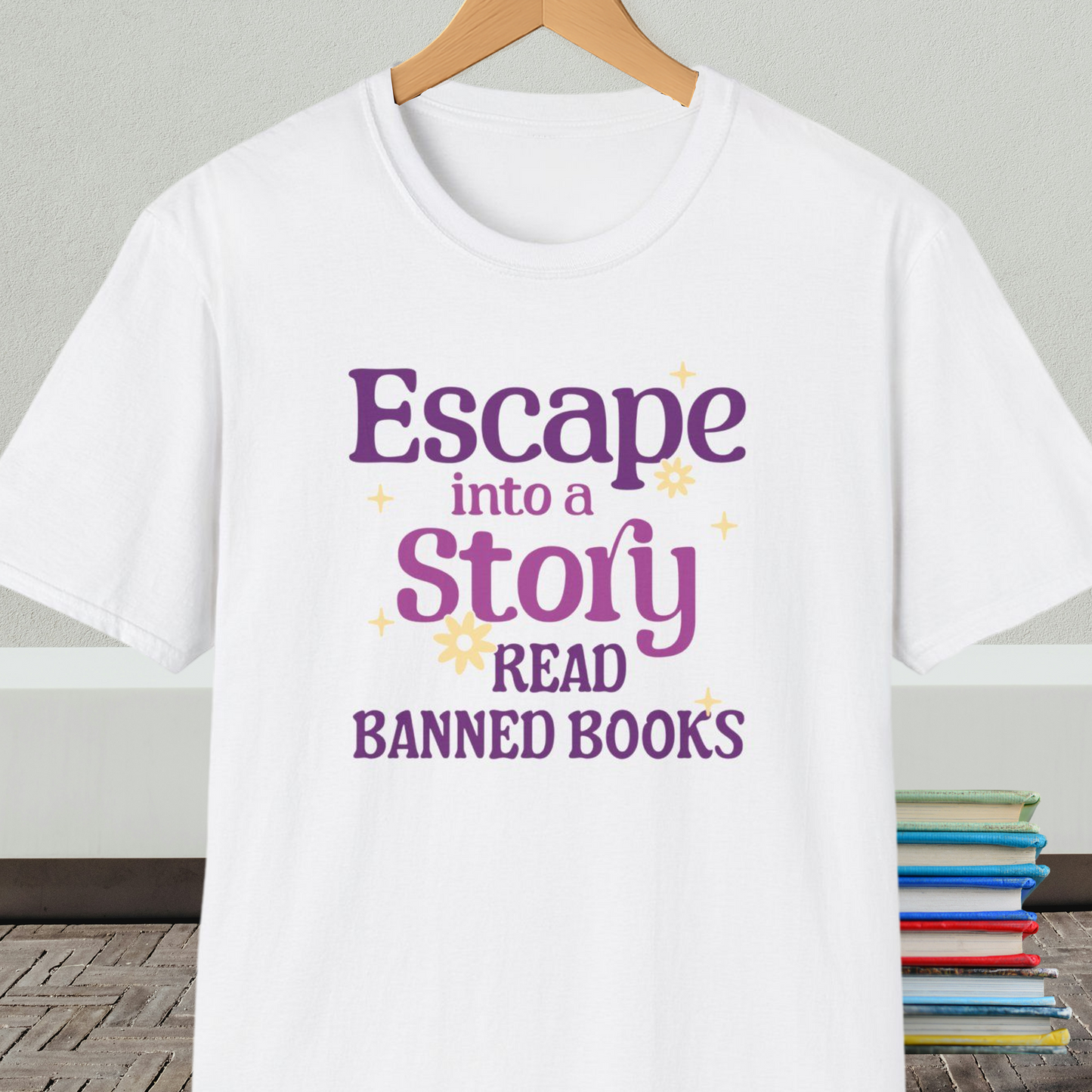 White t-shirt on a hanger, with text 'Escape into a Story, Read Banned Books'