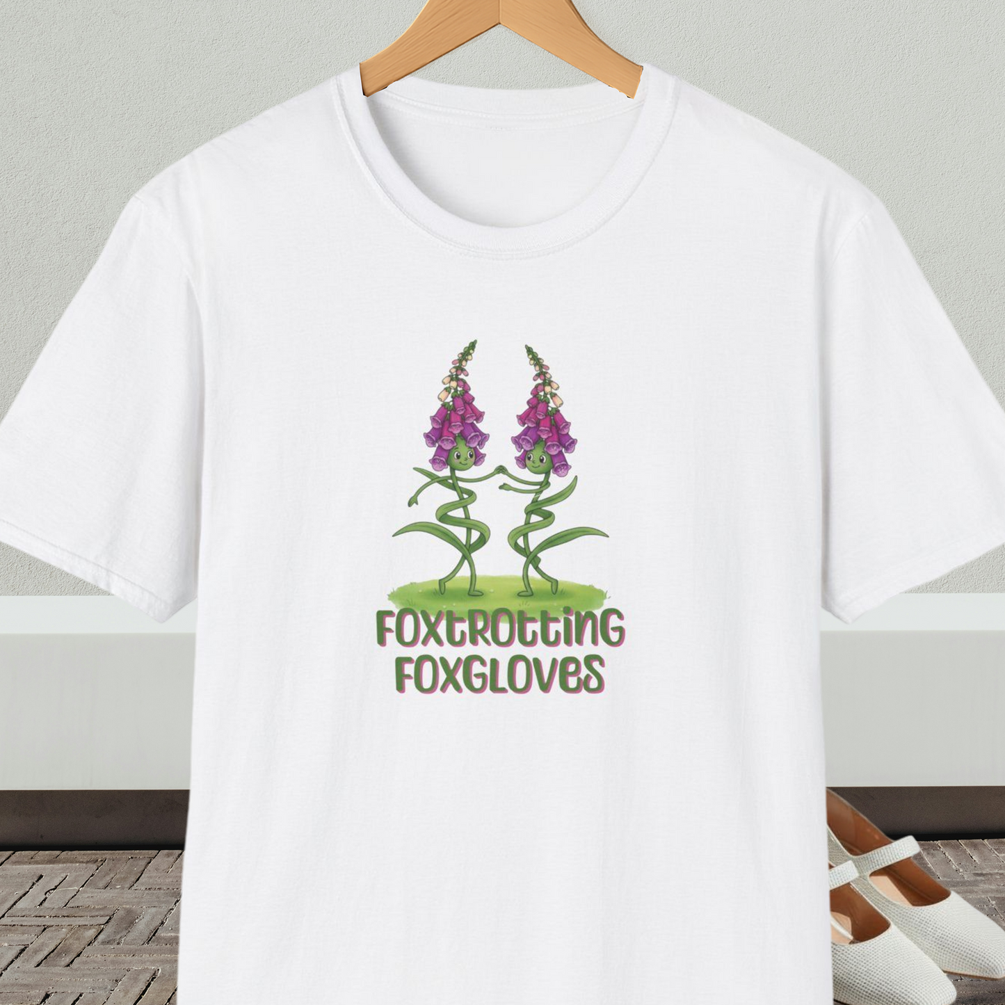 White t-shirt with 'Foxtrotting Foxgloves' design, on a hanger against a neutral background.