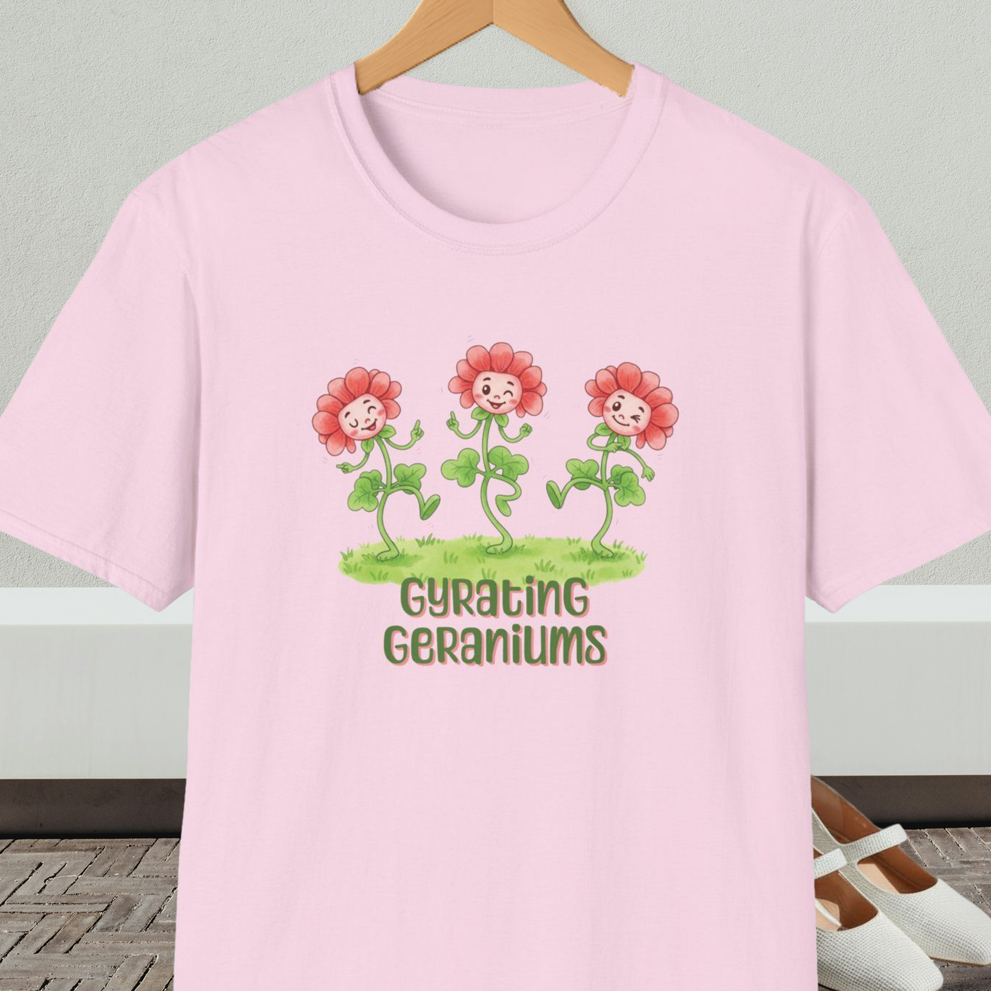 Light pink T-shirt with dancing cartoon flowers and text 'Gyrating Geraniums'