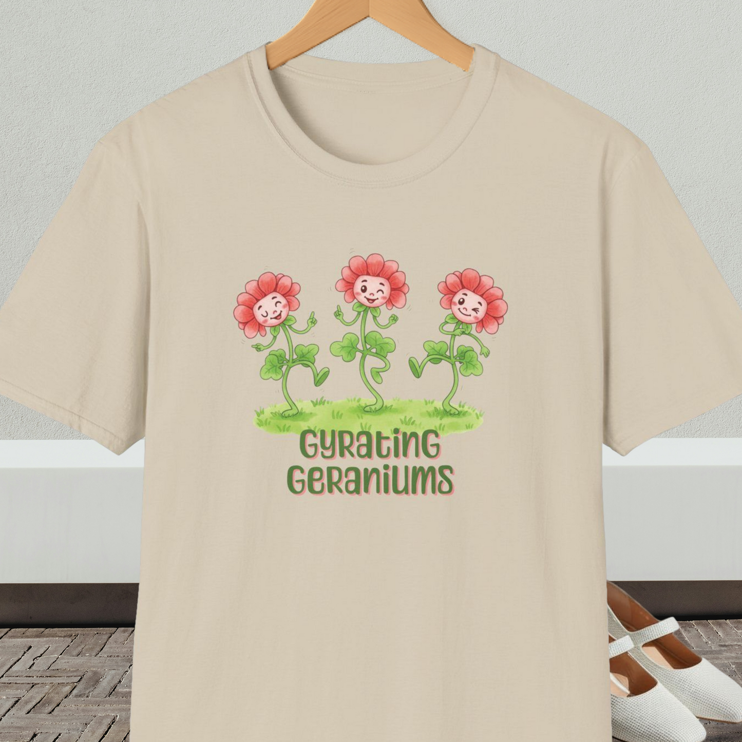 Beige T-shirt with dancing cartoon flowers and text 'Gyrating Geraniums'