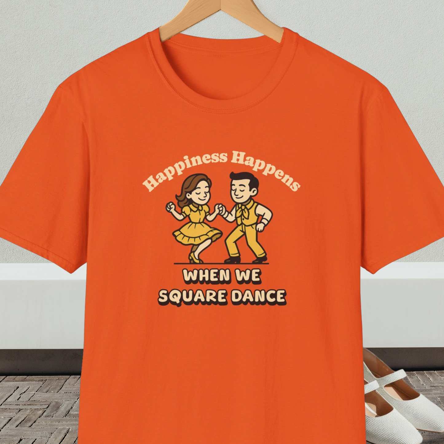 Orange t-shirt with a graphic of two people square dancing and text 'Happiness Happens When We Square Dance'