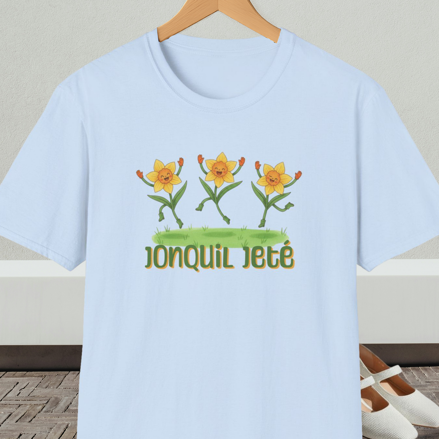 Light blue t-shirt with cartoon dancing jonquils and 'Jonquil Jeté' text.