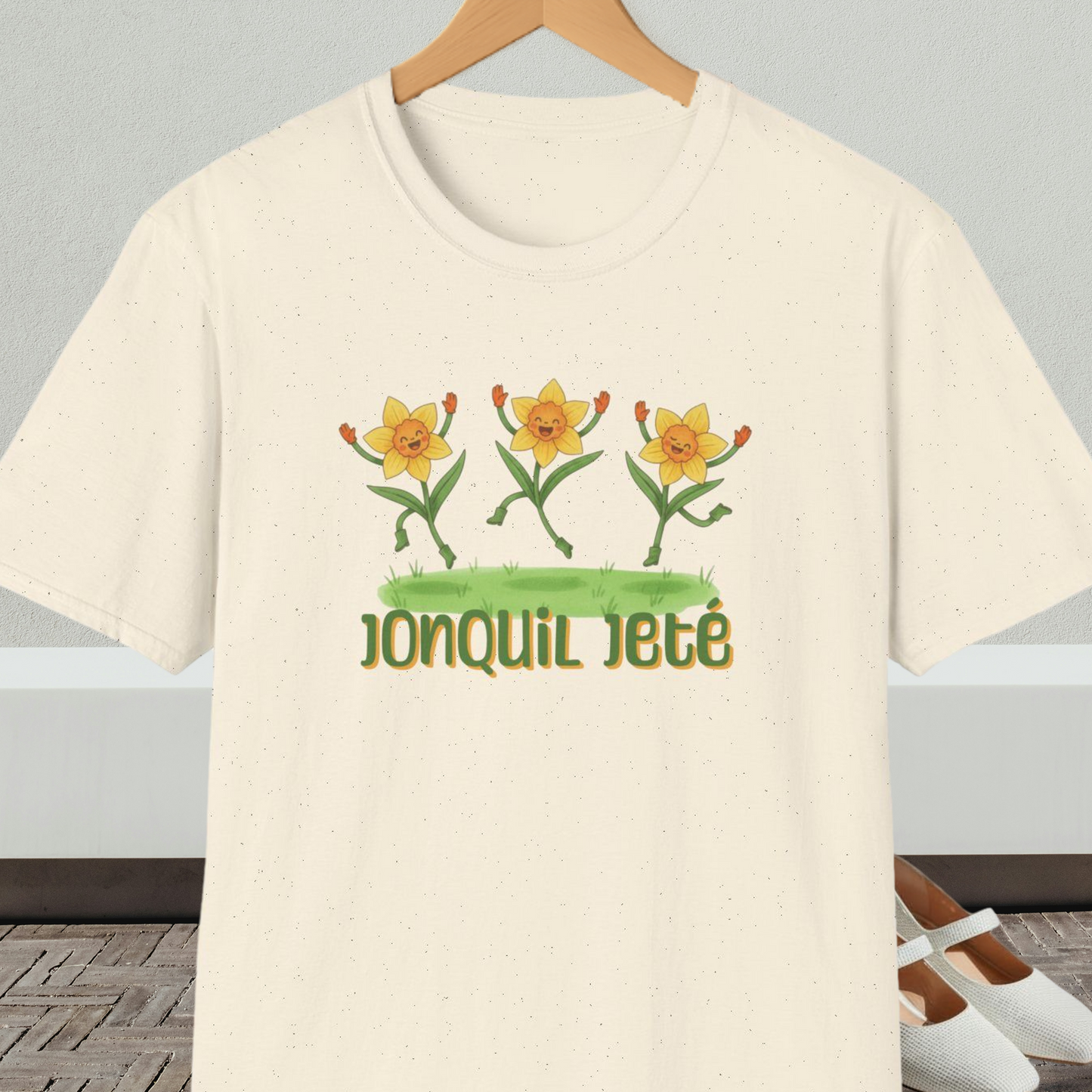Natural beige t-shirt with cartoon dancing jonquils and 'Jonquil Jeté' text.