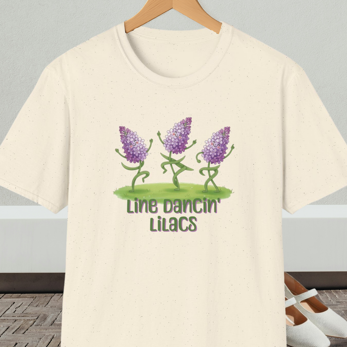 Natural beige t-shirt with text 'Line Dancin' Lilacs' and dancing flowers cartoon design.