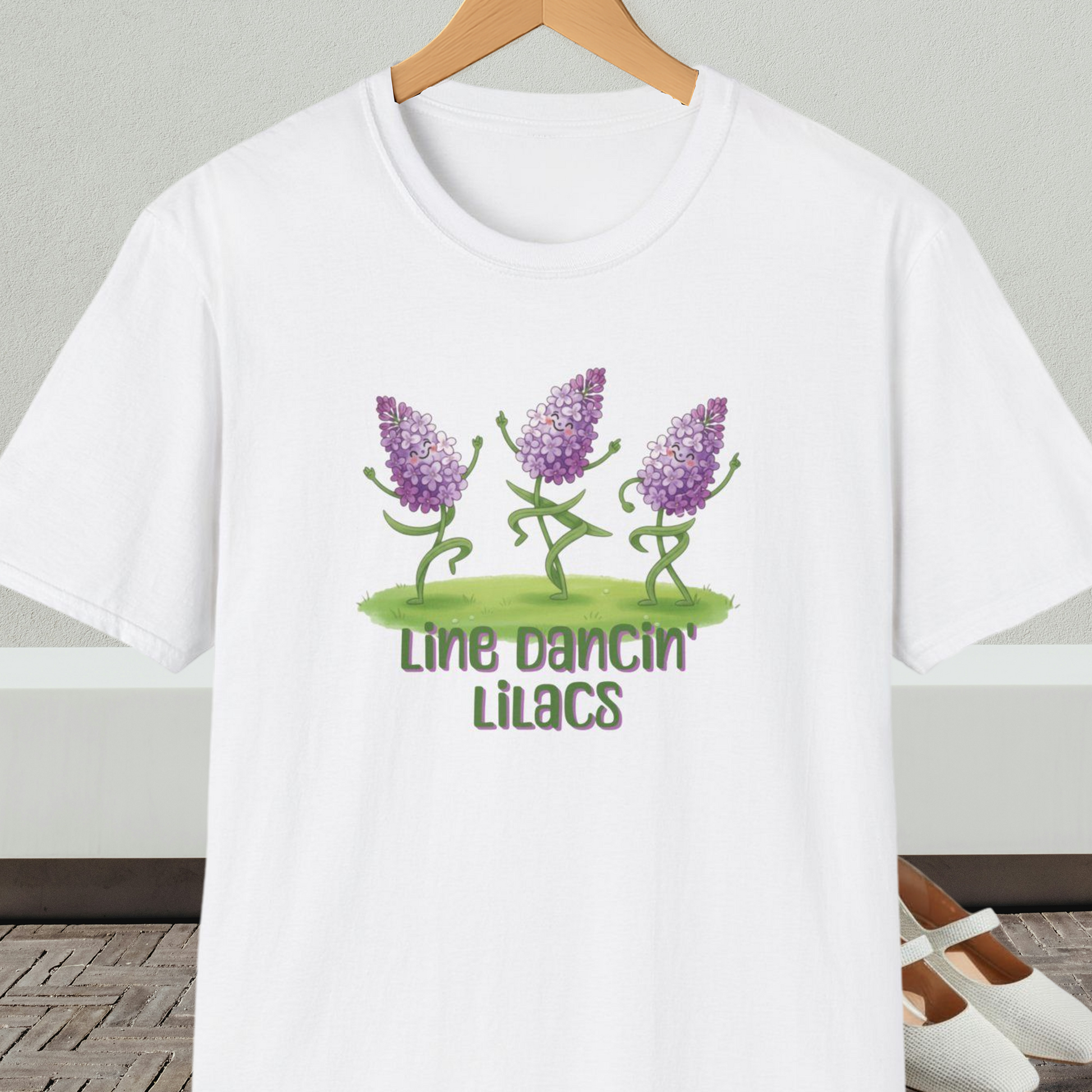 White t-shirt with text 'Line Dancin' Lilacs' and dancing flowers cartoon design.
