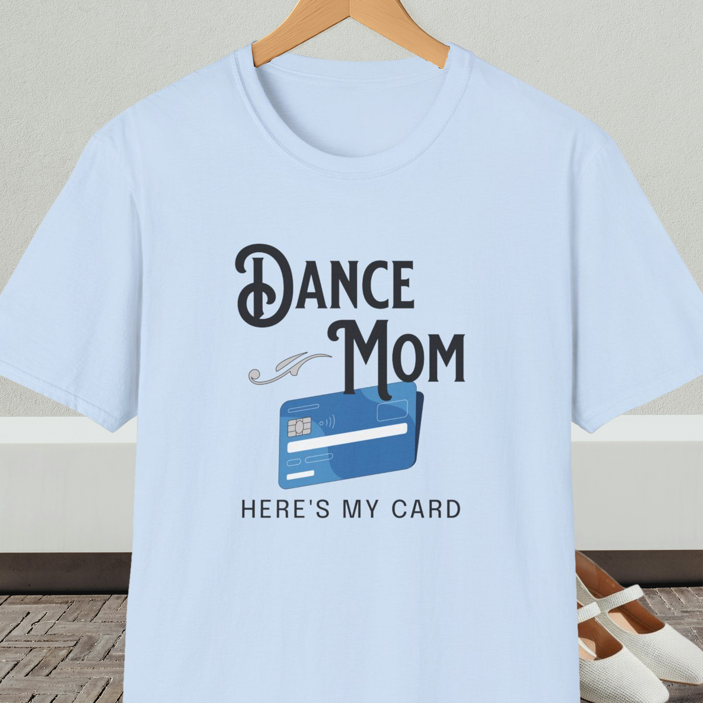 Light blue t-shirt with 'Dance Mom, Here's My Card' text and credit card graphic, on a hanger with a neutral background.