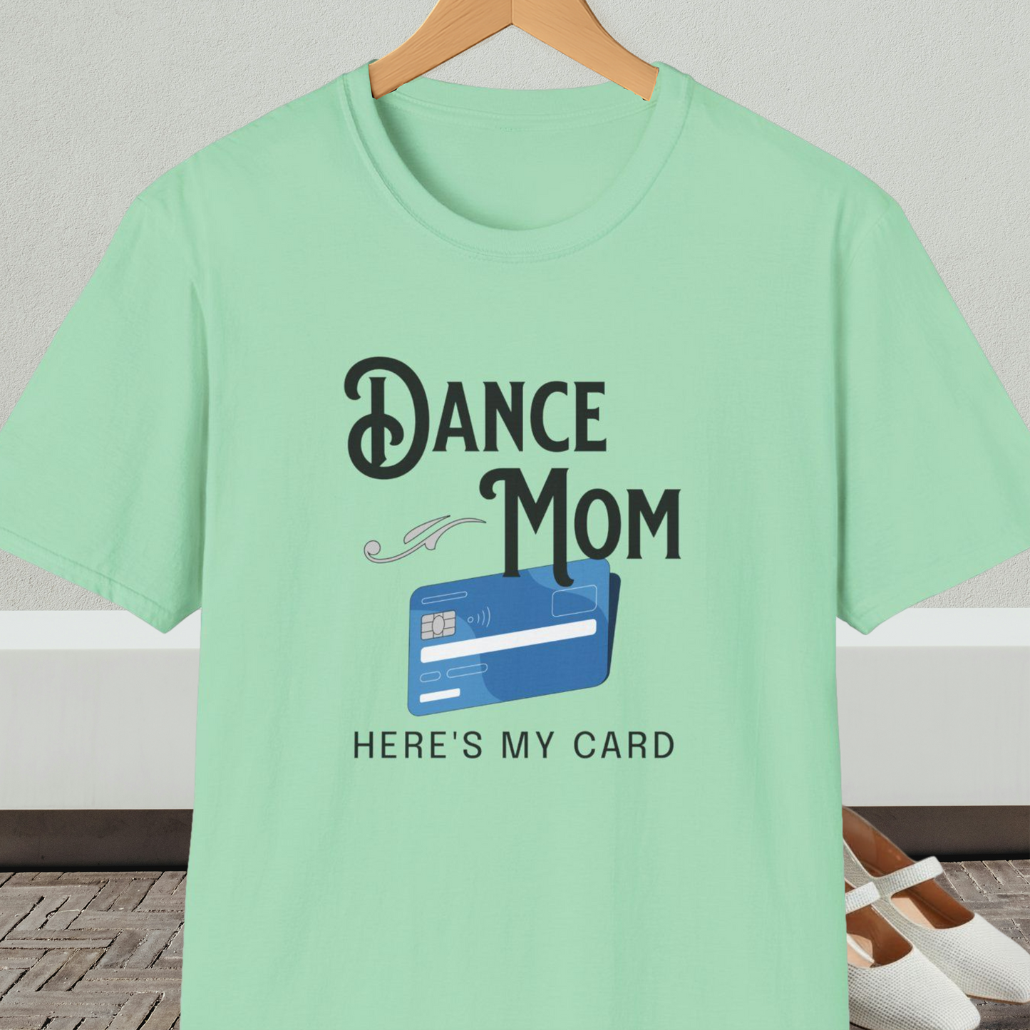 Mint green t-shirt with 'Dance Mom, Here's My Card' text and credit card graphic, on a hanger with a neutral background.