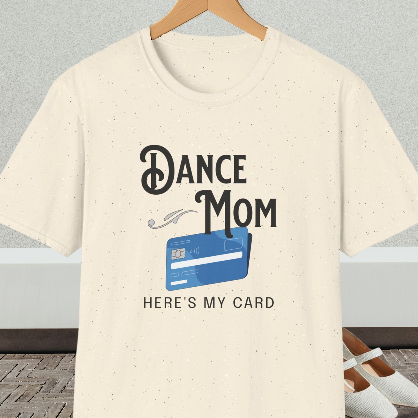 Natural beige t-shirt with 'Dance Mom, Here's My Card' text and credit card graphic, on a hanger with a neutral background.