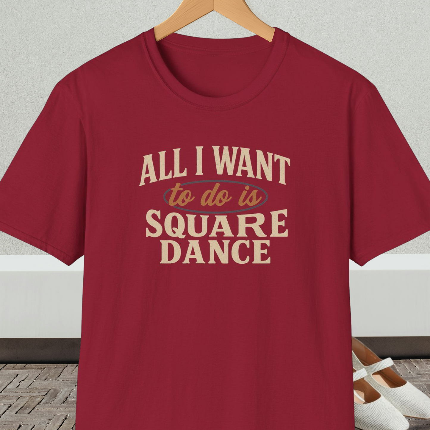 Dark red t-shirt with text 'All I Want to do is Square Dance' on a hanger against a neutral background.