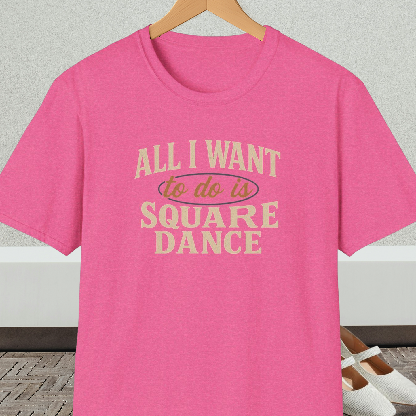 Pink t-shirt with text 'All I Want to do is Square Dance' on a hanger against a neutral background.
