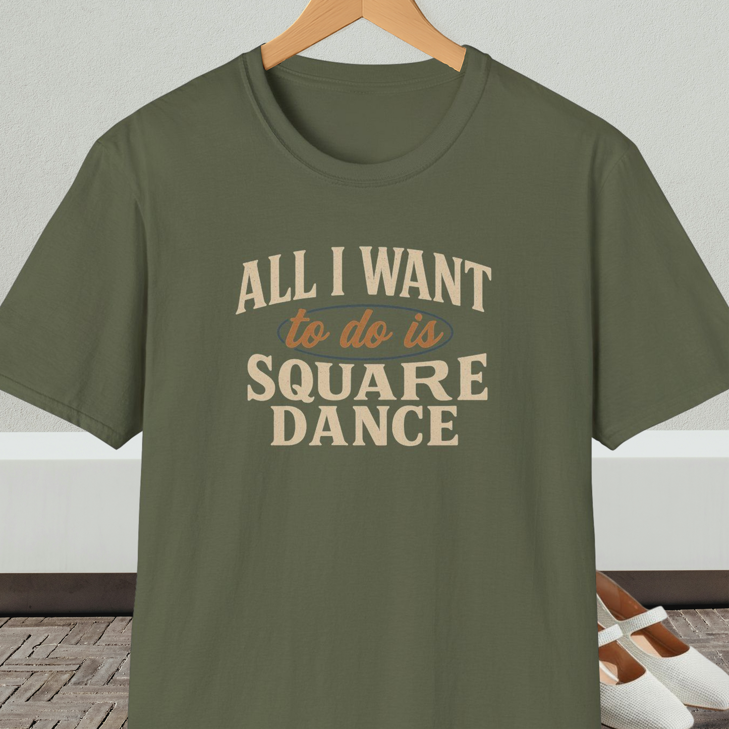 Military green t-shirt with text 'All I Want to do is Square Dance' on a hanger against a neutral background.